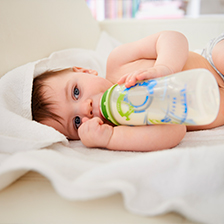 Bambino di pochi mesi beve latte da un Biberon con Stampa Personalizzata